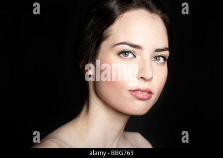 Portrait of a young, dark-haired woman in front of black backdrop Stock Photo