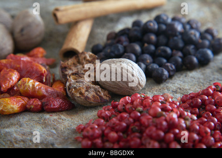 Different spices on a stone slab, juniper, chili peppers, red pepper, nutmeg, cinnamon sticks Stock Photo