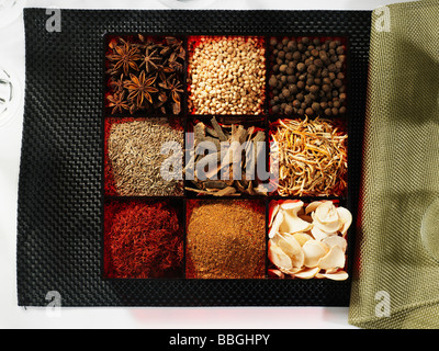 A selection of different spices in a spice box on a black background with a green napkin Stock Photo