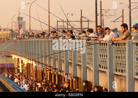 Istanbul Turkey busy scene on the double deck Galata Bridge with local Turkish people fishing in the evening sunshine Stock Photo