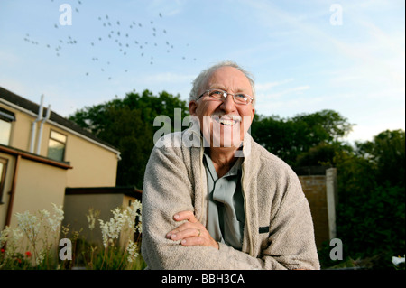 Happy mature man kneeling in his garden Stock Photo