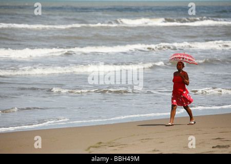 Tasbapauni, Nicaragua; Woman with umbrella walking along the beach Stock Photo