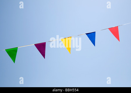 Bunting - triangular flags of different colours against a blue sky Stock Photo