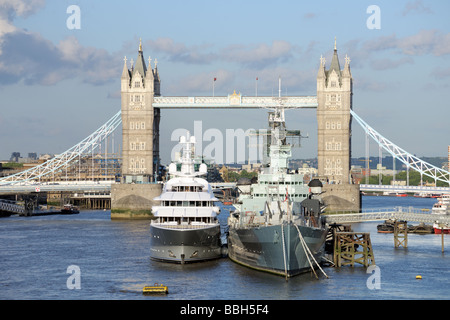 HMS Belfast and a luxury yacht moored on the Pool of London, River Thames, with Tower Bridge in the background Stock Photo