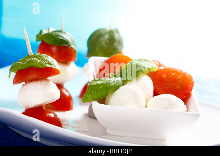 Tomato-mozzarella sticks with basil on a dish Stock Photo