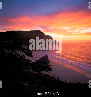 THE SUN RISES BEHIND CAPE POINT REFLECTING ON THE SHORES OF DIAS BEACH Stock Photo