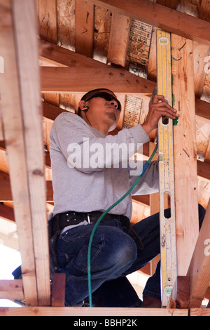 Carpenter using a level to see if a post is plumb on a construction job Stock Photo