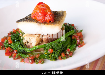 Delectable Atlantic Cod served with fingerling scallion hash braised rapini saffron red peppers and bagna cauda sauce Stock Photo