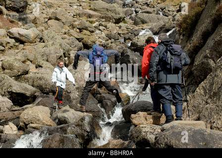 Group of people crossing a waterfall on a rocky mountain in the Lake District Stock Photo