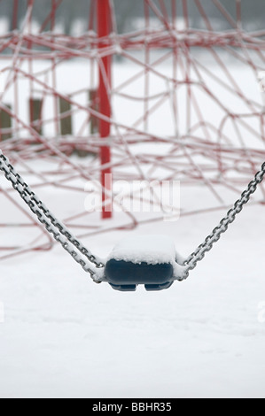 a swing covered with snow on a snowy day in a childrens playground in the uk Stock Photo
