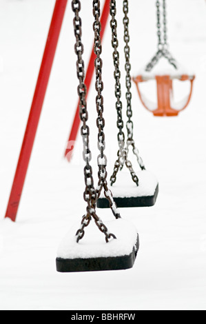 a swing covered with snow on a snowy day in a childrens playground in the uk Stock Photo