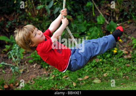 Boy on a rope swing, child swinging on a rope Stock Photo