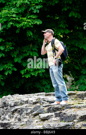 Man with camera using his mobile phone whilst standing on rocks Stock Photo