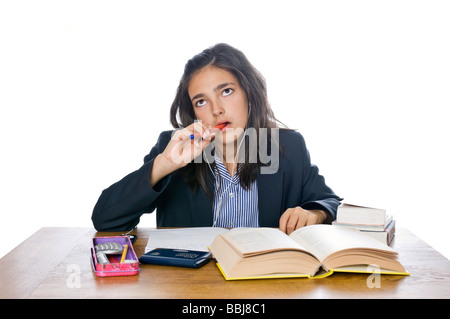 Horizontal portrait of a young school girl in her uniform chewing the end of her pen in concentration whilst doing her homework Stock Photo