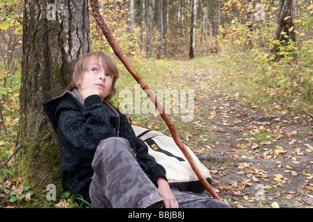 Ten year old boy seated leaning on tree beside trail, Lake Katherine, Riding Mountain National Park, Manitoba Stock Photo