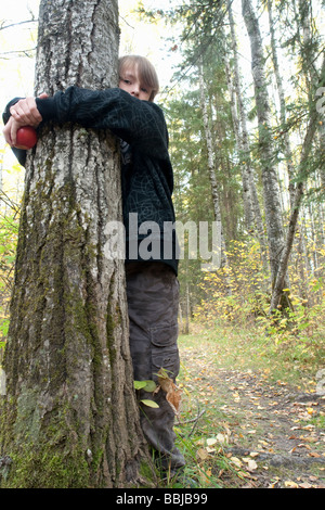 Ten year old boy hugging tree in woods, Lake Katherine, Riding Mountain National Park, Manitoba Stock Photo