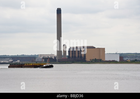 A tug towing barges on the Thames passing Littlebrook Power Station. Stock Photo
