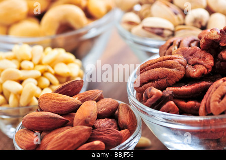 Many glass bowls of almonds walnuts pistachios and pine nuts Stock Photo