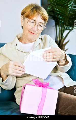 Elderly woman opening birthday card and present Stock Photo