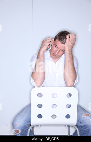 Man talking on cell phone and scratching head Stock Photo