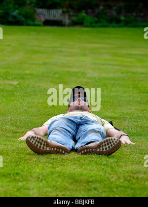 Man laying flat out on a lawn Stock Photo