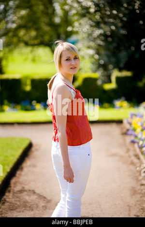 A young woman turns around to look at the camera in a park on a warm summer day. Stock Photo