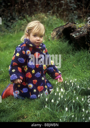 Toddler looking at snowdrops in a garden, Cornwall, UK Stock Photo