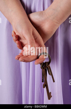 Woman waiting with old rusty keys hiding in her hands Stock Photo
