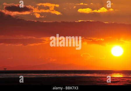 Red sunset and yellow sun sinking off the coast of North Wales, seen from the beach at Lytham, near Blackpool, United Kingdom Stock Photo