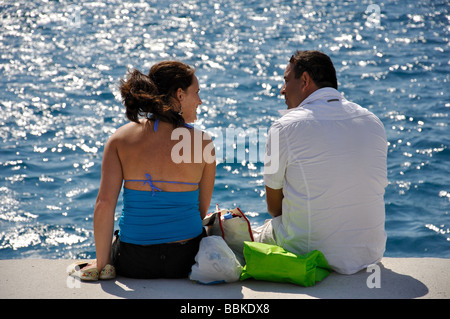 Couple sitting on pier, Old Town, City of Rhodes, Rhodes (Rodos), Dodecanese, Greece Stock Photo