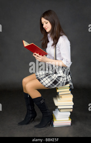 Girl sitting with a pile of books Stock Photo - Alamy