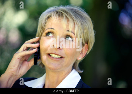Business woman 40 45 years old Wearing a business suite talking on mobile phone outdoor in a park Stock Photo
