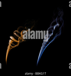 Curls of smoke given off by the combustion of an incense stick. Volutes de fumée dégagées par la combustion d'un bâton d'encens. Stock Photo