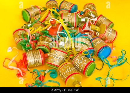 Party poppers on a plain yellow background Stock Photo