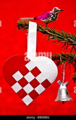 Glass bird and weaved heart on Christmas tree Stock Photo
