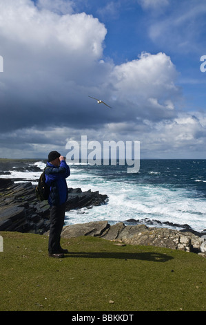 dh Bay of Ryasgeo NORTH RONALDSAY ORKNEY Birdwatcher looking out to sea and rocky coastline