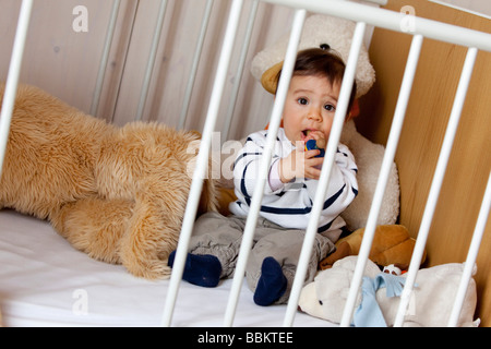 Nine-month-old baby sitting in his cot