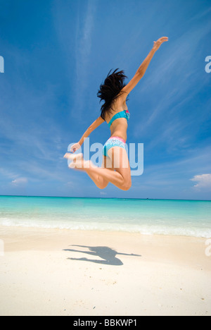 a girl jumping on a beautiful beach
