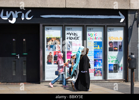 two muslim women and two muslim children walk past the former entrance of the lyric theatre, hammersmith, west london, england Stock Photo