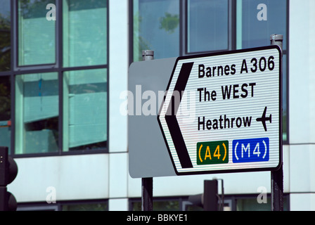 left pointing british road sign showing directions to barnes, the west and heathrow airport, in hammersmith, london, england Stock Photo