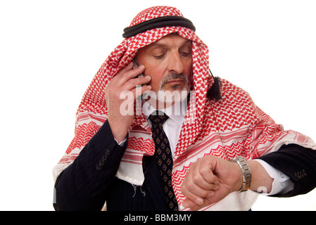 arab businessman checking his watch and using a mobile phone Stock Photo