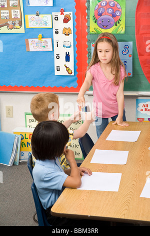 child helping another child 4-5-6 year olds multi ethnic interracial racially diverse multicultural passing supplies five United States  © Myrleen Pearson Stock Photo