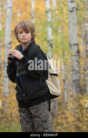 Ten year old boy holding binoculars wearing hemp backpack, Lake Katherine, Riding Mountain National Park, Manitoba Stock Photo