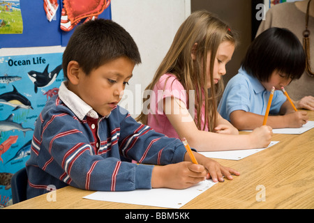 5-6 year old students multi ethnic inter racial diversity racially diverse multicultural cultural interracial write paper POV United States MR Stock Photo