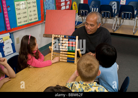 5-6 year old students  ethnic inter racial diversity racially diverse multicultural interracial Filipino volunteer counting abacus POV United States Stock Photo