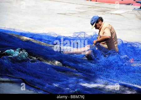 Fisherman mending nets in harbour, Cala Figuera, Santanyi Municipality, Mallorca, Balearic Islands, Spain Stock Photo