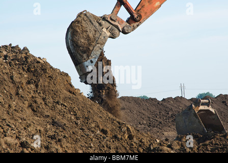 an excavator dumping a bucket of dirt Stock Photo - Alamy