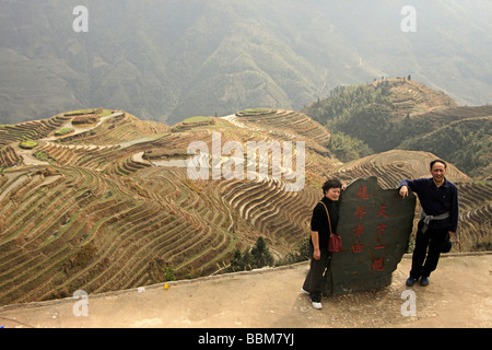 Chinese couple posing in front of the world-famous rice terraces of Longji 'backbone of the dragon' or 'vertebra of the dragon' Stock Photo