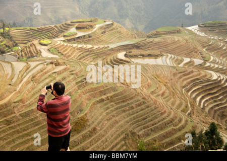 Chinese tourists photographing the world-famous rice terraces of Longji 'backbone of the dragon' or 'vertebra of the dragon' in Stock Photo