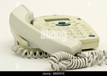 Old style beige telephone with the handset off the hook Stock Photo